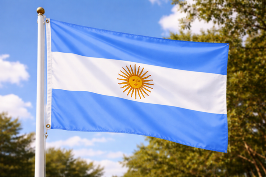 Argentine flag waving against a blue sky with trees in the background