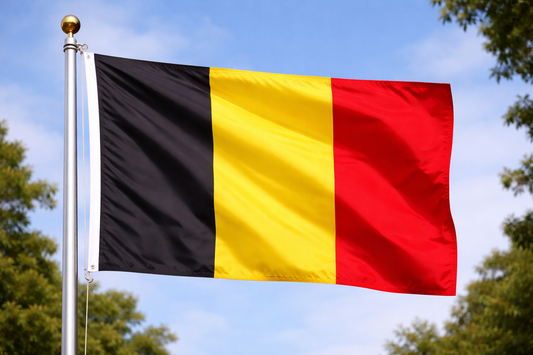 Flag of Belgium waving against a blue sky with trees in the background