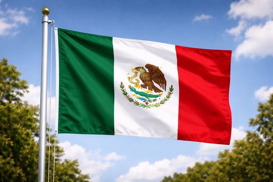 Mexican flag waving against a blue sky with trees in the background