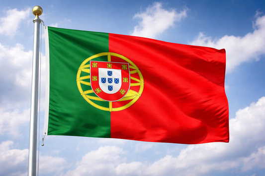 Portuguese flag waving against a blue sky with clouds